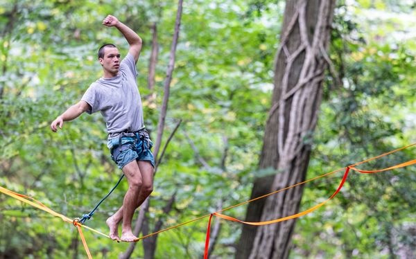 Ein Mensch steht auf einer Highline im Wald